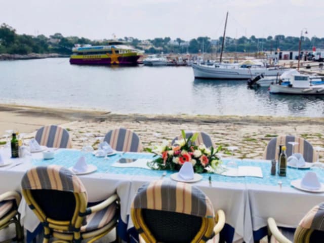 Mesa preparada con mantel y flores frente a las embarcaciones amarradas en el puerto